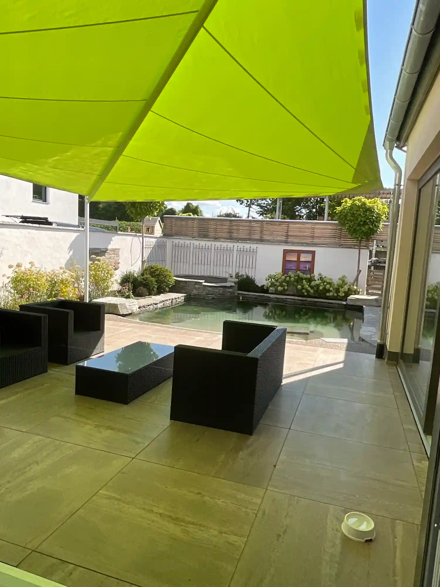 Grünes Sonnensegel über einer Terrasse mit Pool.